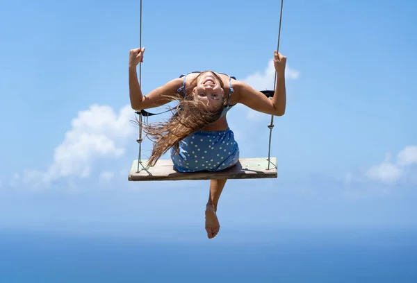 Joven hermosa mujer caucásica en el columpio de cuerda con fondo de mar y cielo. Concepto de libertad y felicidad — Foto de Stock