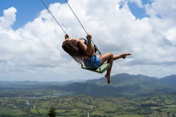 Mujer joven en el columpio cuerda con el cielo y las montañas de fondo. Concepto de vacaciones y viajes — Foto de Stock
