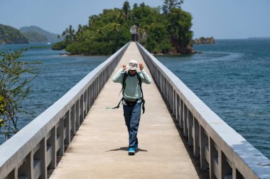 Köprüde sırt çantalı yalnız bir yürüyüşçü var. Adaya gidiyor. Seyahat ve macera konsepti 