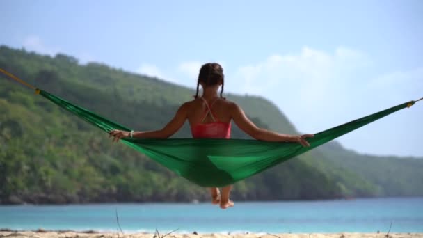 Silueta ženy v houpací síti, která zpomaleně hledí na tropickou pláž. Koncept dovolené a cestování — Stock video