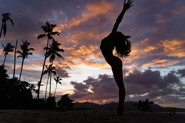 Silueta de mujer durante el atardecer tropical con palmera y nubes dramáticas. Concepto de vacaciones y resort. — Foto de Stock