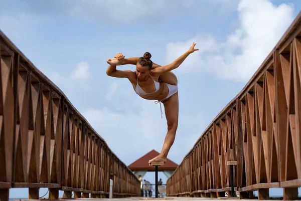 Artista de circo femenino flexible mantener el equilibrio en división en el puente. Vida sana, yoga y concepto de flexibilidad — Foto de Stock