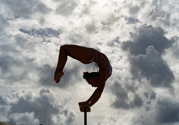 Artista de circo femenino flexible mantener el equilibrio en las manos contra el paisaje nublado increíble. Individualidad, excepcional y originalidad. — Foto de Stock