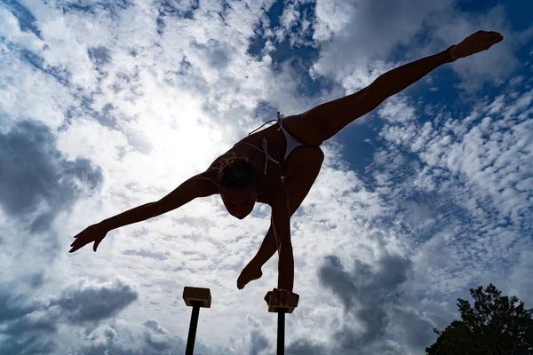 Artista de circo femenino flexible mantener el equilibrio por un lado contra el paisaje nublado increíble. Motivación, pasión y concepto de logro — Foto de Stock