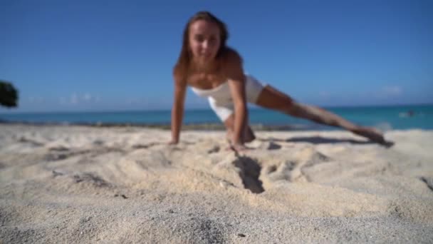 Ung vältränad kvinna dansar och leker med sand på stranden i slow motion. Begreppet semester, resor och semesteranläggningar — Stockvideo