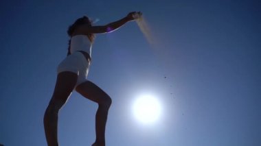 Kum kadınların parmaklarından süzülür, gökyüzü arka planında ağır çekimde. Zaman geçişi kavramı 