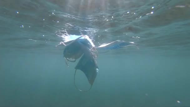 Beschermende gezichtsmaskers tegen het coronavirus dat onder water zweeft. Verontreiniging van het milieu en ecologisch vraagstuk — Stockvideo