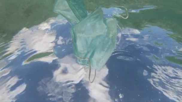 Mundschutz vor Coronavirus, das unter Wasser schwimmt. Umweltverschmutzung und ökologisches Problemkonzept — Stockvideo