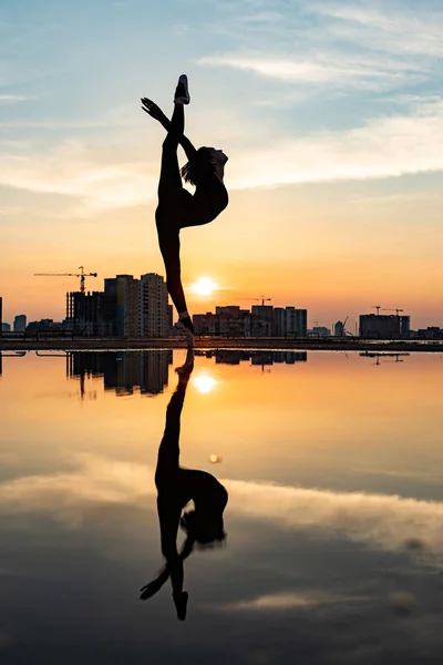 Silueta de bailarina actuando al aire libre durante el atardecer. Concepto de individualidad, creatividad y confianza en sí mismo — Foto de Stock