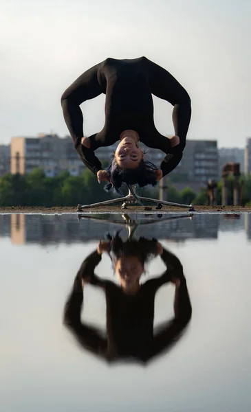 Flexibel en fit meisje buigt haar rug ondersteboven met reflectie in het water. Begrip individualiteit, creativiteit en uitmuntend — Stockfoto