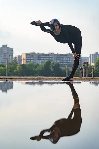 Flexibel en fit meisje houden evenwicht op een vin in split. Concept van yoga, controle en gezonde levensstijl — Stockfoto