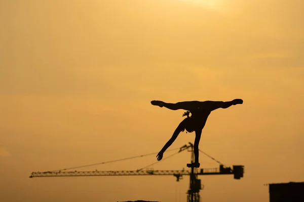 Silueta de acróbata flexible haciendo handstand sobre el dramático fondo del atardecer. Concepto de fuerza de voluntad, control y sueño — Foto de Stock