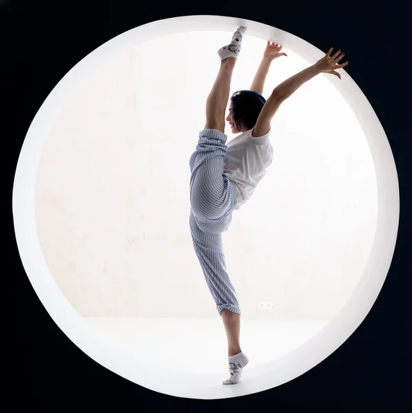 Esnek kız stüdyoda esneme hareketleri yapıyor. İrade, motivasyon ve sağlıklı yaşam tarzı kavramı