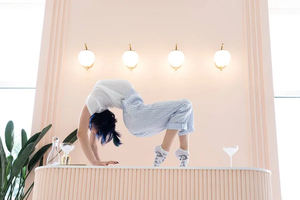 Flexibel kvinna står vid bordet med glas vatten. Begreppet yoga och hälsosam livsstil — Stockfoto