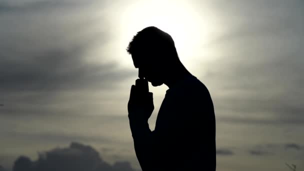 Silueta del Hombre rezar durante la puesta del sol. Concepto de religión, fe y esperanza — Vídeo de stock