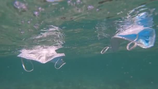 Máscaras protetoras contra coronavírus a flutuar debaixo de água. Poluição do ambiente e conceito de questão ecológica — Vídeo de Stock