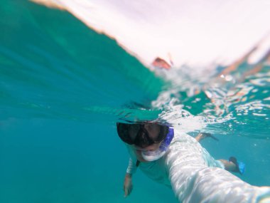 Adam su altında şnorkelle yüzüyor. Mavi berrak su. Uzayı kopyala Seyahat ve macera kavramı