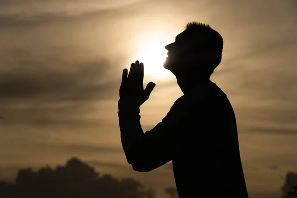 Silhouette de l'homme prier pendant le coucher du soleil. Repentance, regret et espoir concept — Photo