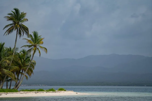 Крихітний тропічний, незаселений острів з пальмами та білим піщаним пляжем в похмуру погоду з місцем для тексту. Концепція відпустки та подорожей — стокове фото