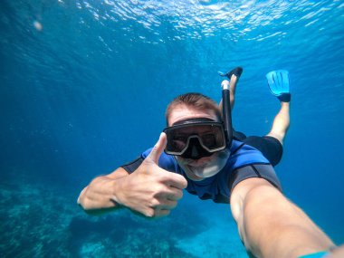 Şnorkel maskeli bir adam suyun altında selfie çekiyor. Tatil, serbest dalış ve seyahat konsepti.