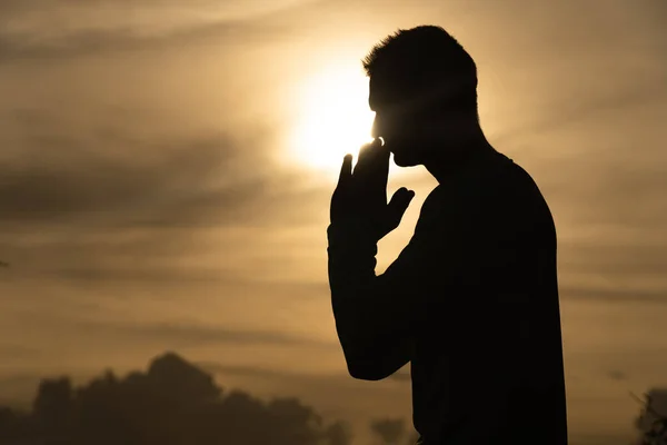 Silhouette de l'homme prier pendant le coucher du soleil. Religion, foi et espérance concept — Photo