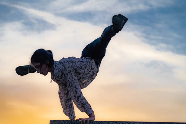 Silueta de gimnasta mujer flexible haciendo handstand en el atardecer dramático. Concepto de fuerza de voluntad, motivación y pasión — Foto de Stock