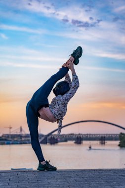 Esnek kadın silueti dramatik günbatımında jimnastik dengesini koruyor. Bireysellik kavramı, yaratıcılık ve olağanüstü