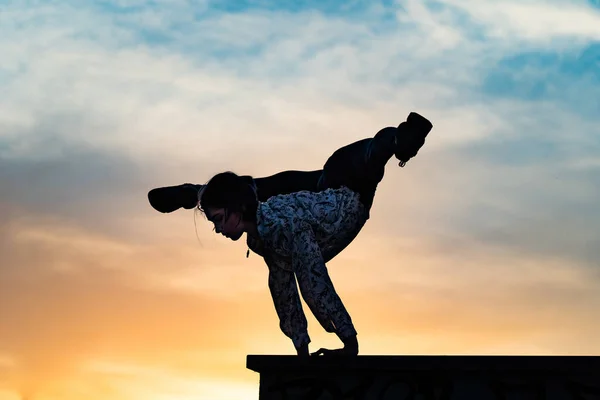 Silueta de artista de circo femenino flexible haciendo de pie de manos en la dramática puesta de sol. Concepto de individualidad, creatividad y sobresaliente — Foto de Stock
