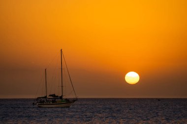 Yelkenli silueti ve güneş diski ile güzel bir gün batımı. Seyahat ve tatil kavramı 