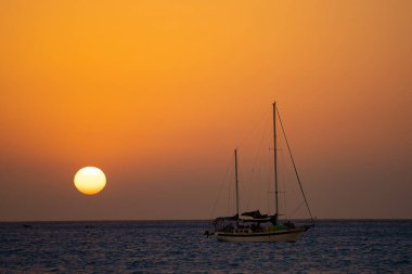 Yelkenli silueti ve güneş diski ile güzel bir gün batımı. Seyahat ve macera konsepti 