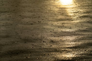 Gün batımında su yüzeyinde hafif yağmur damlaları