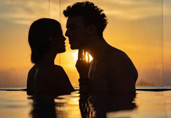 Silhueta de casal amoroso na água do pólo infinito durante o pôr do sol. Romance e relacionamento — Fotografia de Stock