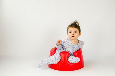 plastik bir koltukta oturan şirin bebek kız