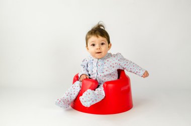 plastik bir koltukta oturan şirin bebek kız