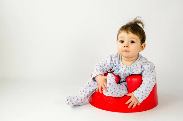 Cute baby girl sitting in a plastic seat — Stock Photo, Image