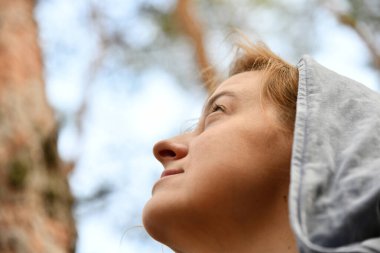 Evergreen Pine Ormanı 'nda sırt çantası ve kapüşonlu bir turist. Seyahat, eko-turizm, ekoloji konsepti, kapüşonlu ve kozalaklı ağaçlar içinde bir kaşifle doğal arka plan.