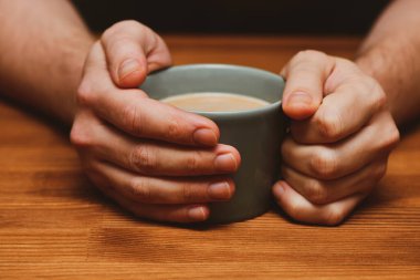 Genç adam sıcak çikolata ya da kahve içiyor. Sonbahar ya da kış karamsar hafta sonu, yeni yıl ve Noel geçmişi. Tembel gün, karantina, evde kal, rahat sahne, kızlık zarı konsepti.