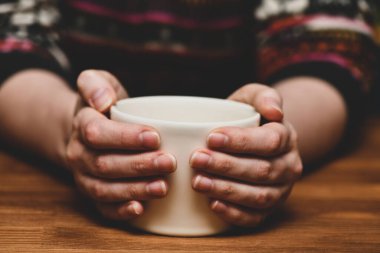 Elinde sıcak kakao ya da kahve fincanı tutan genç bir kadın. Sonbahar ya da kış karamsar hafta sonu, yeni yıl ve Noel geçmişi. Tembel bir gün, hafif bir kahvaltı, karantina, evde kal, rahat sahne, kızlık zarı konsepti..