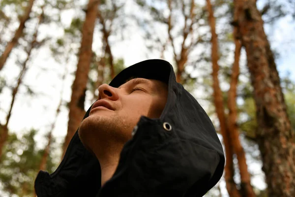 A young man inhales clean forest air on his full chest. Breath in breath out. Breathing exercises. Travel, ecotourism, ecology, local tourism, success concept, natural background.