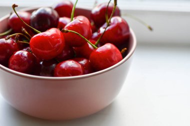 A handful of juicy, ripe cherries in a cute pink bowl