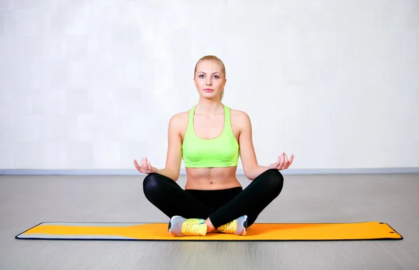 Young fitness woman doing yoga exercises sitting in lotus position — Stock Photo, Image