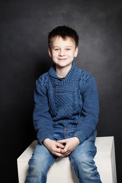 Mosolygó gyermek fiú kék pulóver a sötét háttér — Stock Fotó