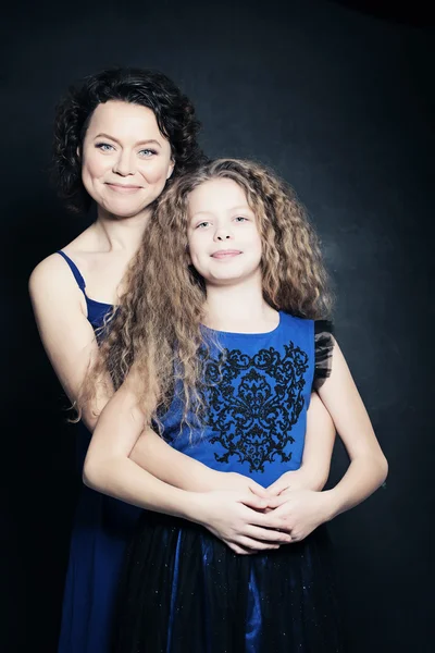 Hermosa madre e hija abrazando sobre fondo azul —  Fotos de Stock