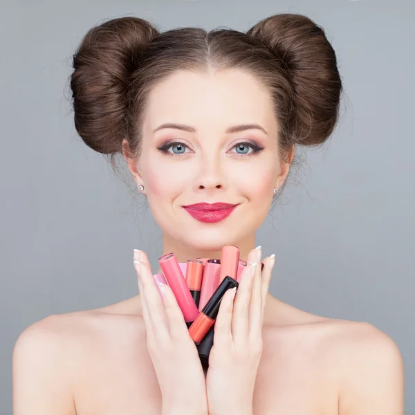 Maquiagem. Menina bonita segurando batons brilhantes e batom — Fotografia de Stock