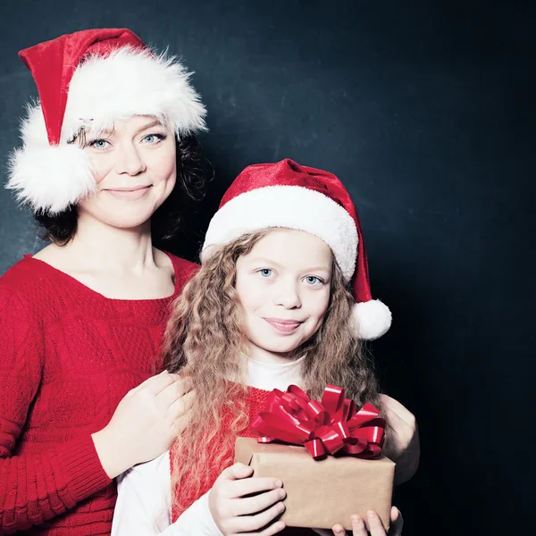 Glückliche Mutter und Tochter im Weihnachtsmannhut mit Weihnachtsgeschenk — Stockfoto