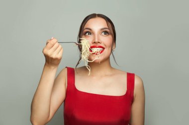 Genç mükemmel kadın beyaz arka planda İtalyan spagettisi yiyor.