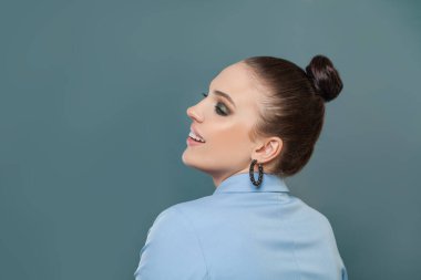 Mutlu esmer kadın mavi arka plana bakıyor.