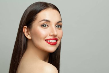 Açık tenli, uzun, sağlıklı saçlı, beyaz arka planda gülümseyen mutlu genç kadın yüzü.