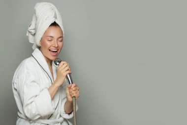 Genç mutlu kadın duş alıyor ve şarkı söylüyor.