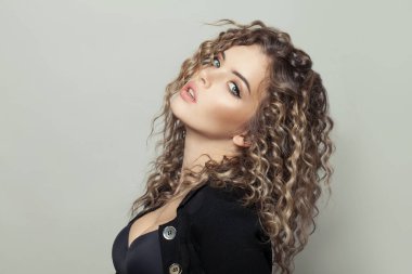 Beyaz arka planda kıvırcık saçlı çekici bir genç kadın.